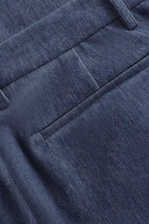 Detail view of the back pocket on men’s indigo rinse structured denim trousers.