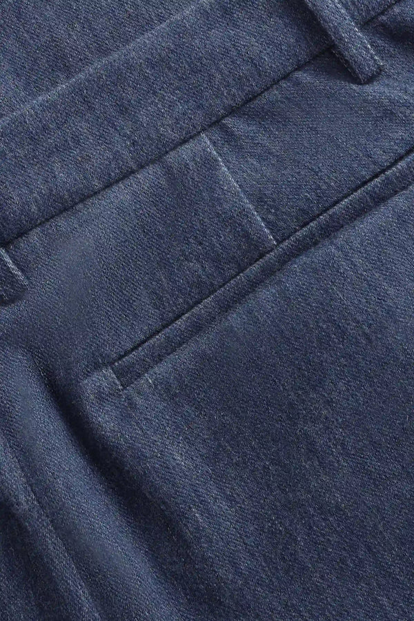 Detail view of the back pocket on men’s indigo rinse structured denim trousers.