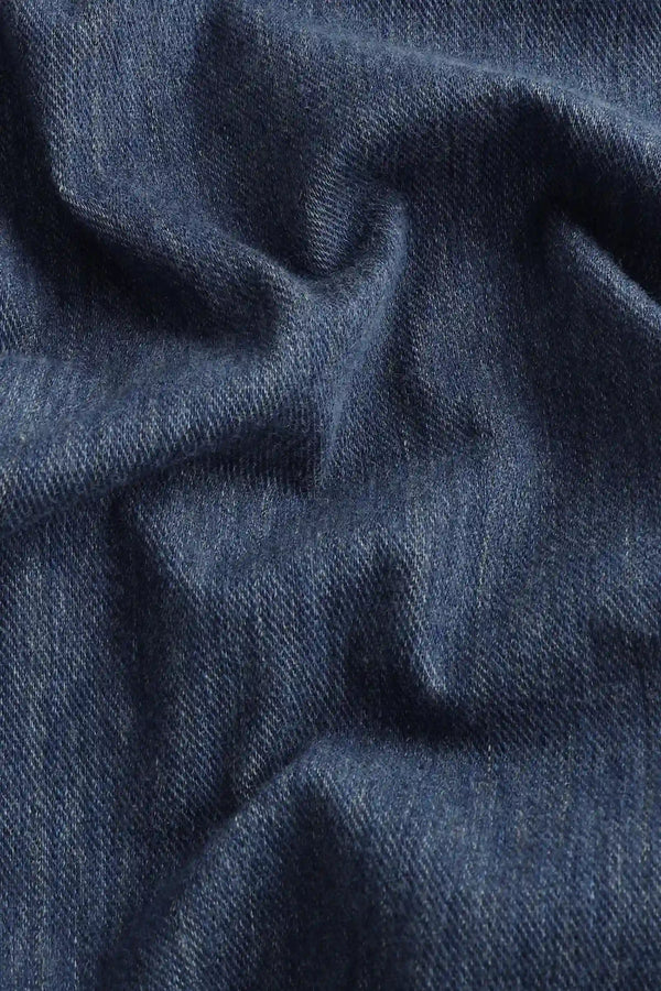 Close-up of the indigo rinse structured denim fabric, highlighting a crisp hand feel and refined texture.