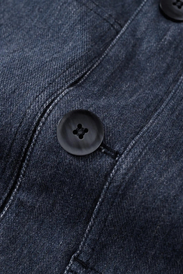 Detail view of the button closure on a men’s indigo rinse utility denim overshirt jacket.