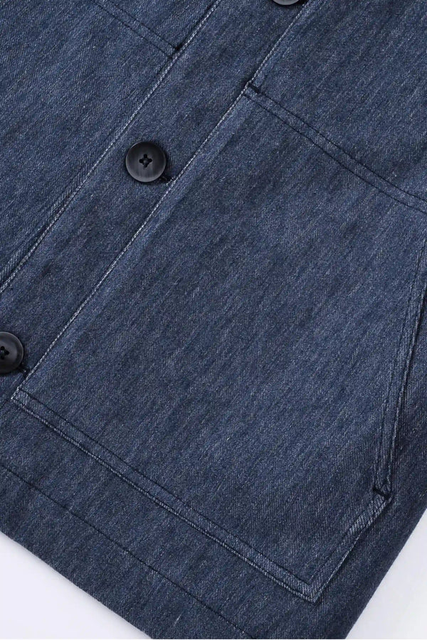 Close-up of the hem finish on a men’s indigo rinse utility denim overshirt jacket, showing a clean, structured edge.