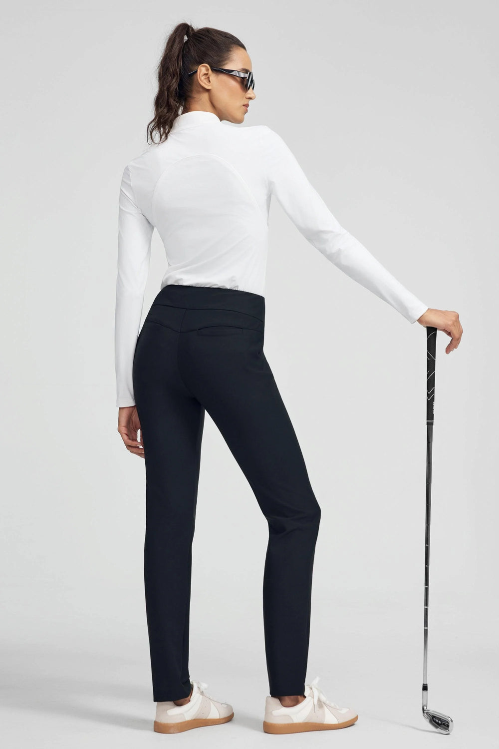Woman wearing VEZA onyx black 4-way stretch tailored pant styled with a white performance top, front view
