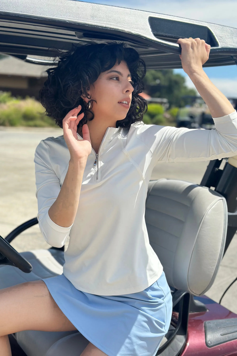 Woman wearing VEZA white piped quarter-zip performance top with UPF 50+, styled with a black skirt, front view