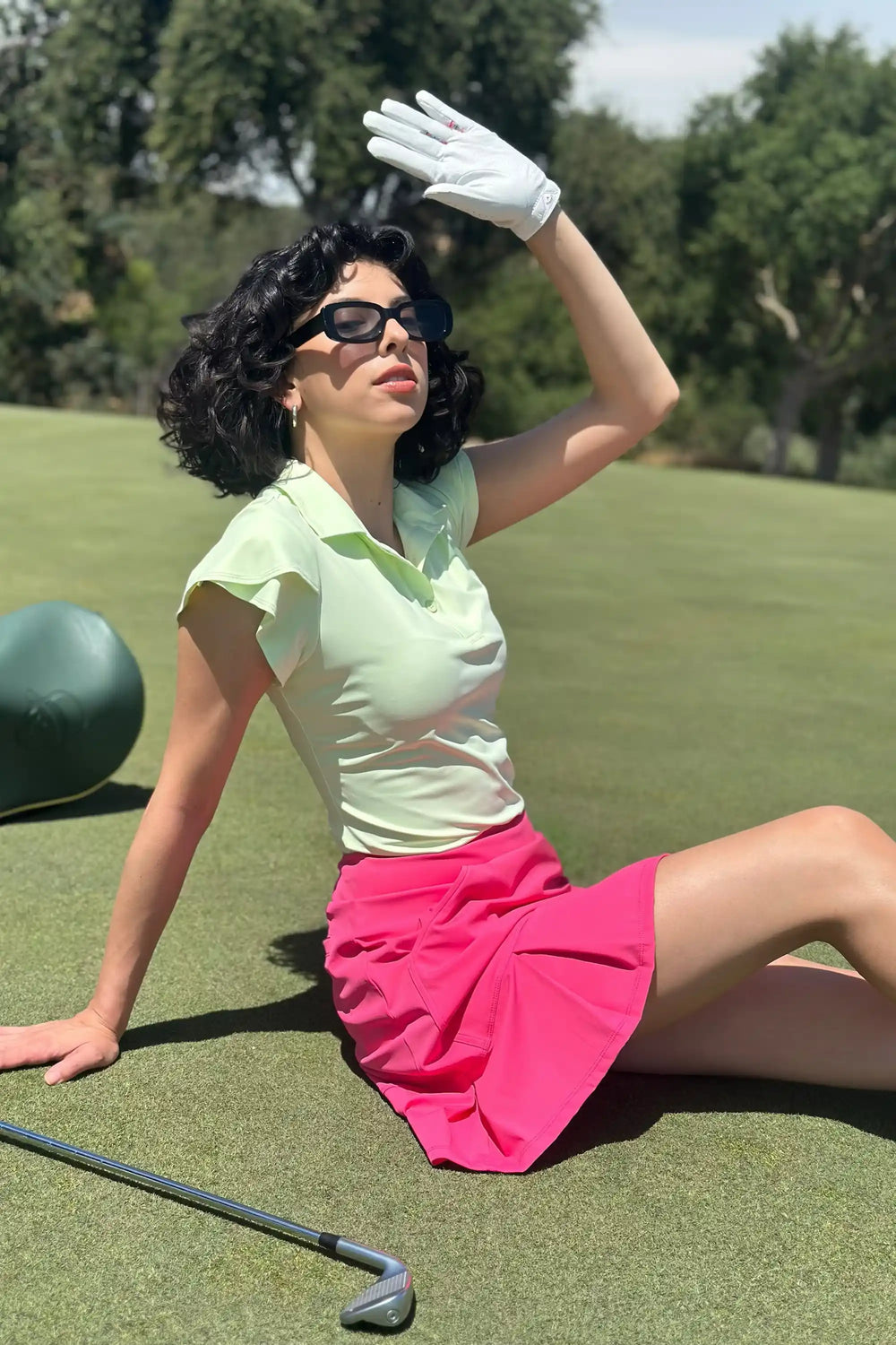 Woman wearing VEZA fairway mint ruffle-sleeve performance golf polo with UPF 50+, styled with a white golf skirt, front view