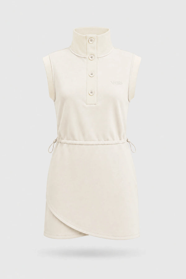 Front view of women's ivory sleeveless golf dress with buttoned stand collar, drawcord waist and asymmetric wrap hem