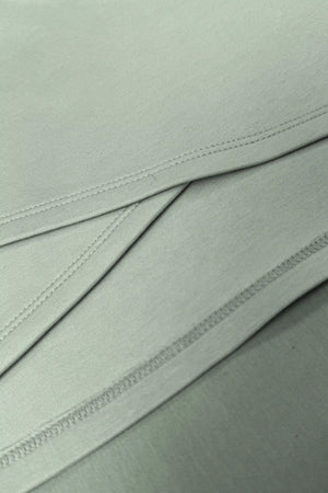 Close-up of the asymmetric wrap construction and clean stitching on the Sage Mist women’s golf dress