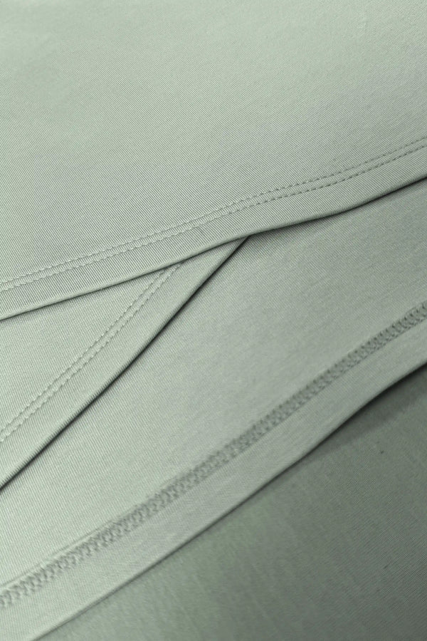 Close-up of the asymmetric wrap construction and clean stitching on the Sage Mist women’s golf dress