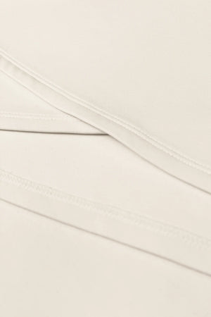 Close-up of the asymmetric wrap construction and clean stitching on the Soft Ivory women’s golf dress