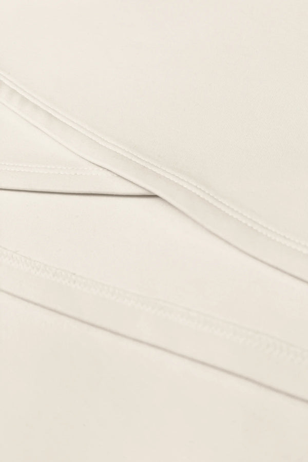 Close-up of the asymmetric wrap construction and clean stitching on the Soft Ivory women’s golf dress